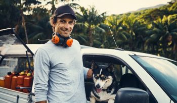 Portrait of a happy landscaper petting his dog while standing next to his vehicle