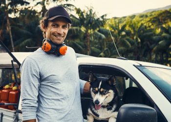Portrait of a happy landscaper petting his dog while standing next to his vehicle