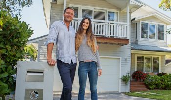couple standing by their mailbox in front of new home