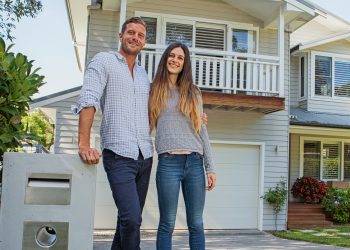 couple standing by their mailbox in front of new home