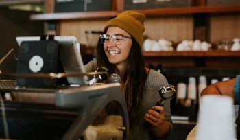 Staff Member smiling while making a coffee at a coffee machine