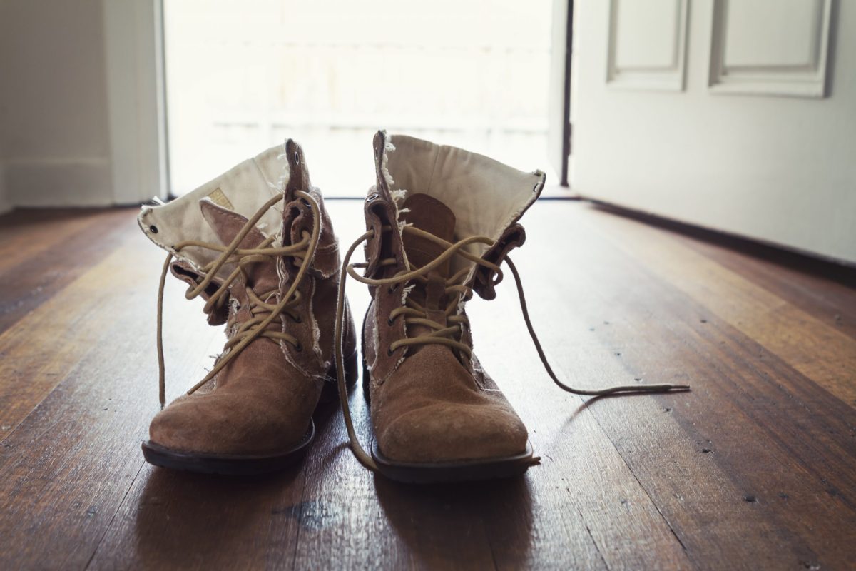 Pair of men's worn leather boots in doorway of home tradies