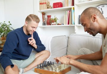Men sitting on sofa playing chess smiling