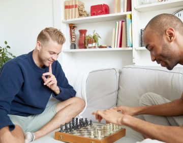 Men sitting on sofa playing chess smiling